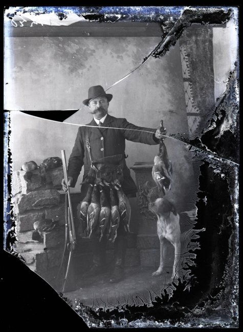   Staand portret, man met brede snor in jagerskostuum met geweer, jachthond en jachttrofeeën, Melle , 1910-1920