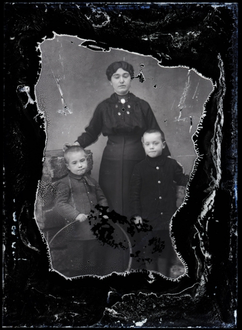 Staand portret van jonge moeder in donkere feestkledij, opgestoken haar, 2 jongentjes  , Melle , 1910-1920