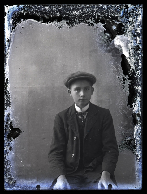 Zittend portret van jonge man in kostuum met wit hemd en stropdas, hoofddeksel, Melle , 1910-1920