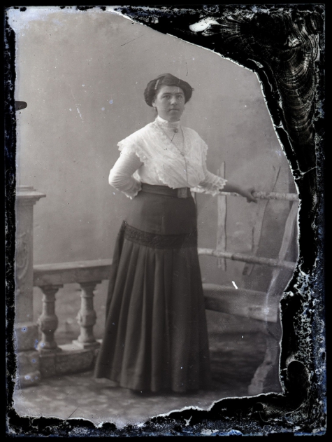 Staand portret van jonge vrouw in feestkledij bestaande uit lange rok en witte bloes, opgestoken haar met insteekkam, Melle , 1910-1920