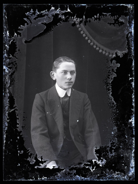 Zittend portret jonge man in feestkledij, bestaande uit kostuum en opgezette witte hemdskraag met stropdas, Melle , 1910-1920