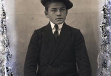 Zittend portret van jonge man in feestkledij met wit hemd stropdas en pet, Melle , 1910-1920