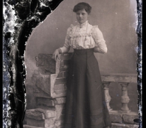 Rechtstaande jonge vrouw met lange rok, opgesmukte blouse, lange halsketting, Melle, 1910-1920