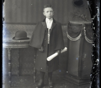 Staand portret van jongeman, feestkledij met lange mantel en lederen handschoenen, opgerold dokument in linkerhand, Melle , 1910-1920