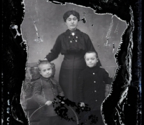 Staand portret van jonge moeder in donkere feestkledij, opgestoken haar, 2 jongentjes  , Melle , 1910-1920