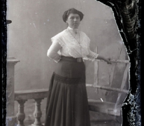 Staand portret van jonge vrouw in feestkledij bestaande uit lange rok en witte bloes, opgestoken haar met insteekkam, Melle , 1910-1920