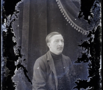Zittend portret man van middelbare leeftijd met vest en gestreepte pullover met hoge kraag, strak opzijgekamd haar, Melle , 1910-1920