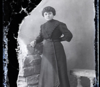 Staand portret van jonge vrouw in donkere feestkledij met golvend opgestoken haar, Melle, 1910-1920