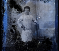Staand portret van jongen in bakkersschort en donkere pet, Melle, 1910-1920