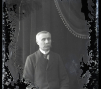 Zittend portret van man in feestkledij met wit hemd en stropdas, gemodelleerde snor en glad naar rechts gekamd haar, Melle, 1910-1920 Zittend portret van man in feestkledij met wit hemd en stropdas, gemodelleerde snor en glad naar rechts gekamd haar, Melle, 1910-1920
